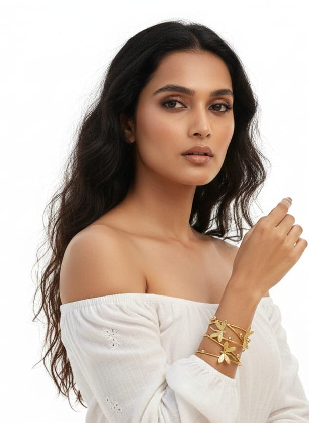 Woman wearing a white off-shoulder top with gold jewelry on a white background