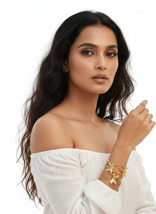 Woman wearing a white off-shoulder top with gold jewelry on a white background